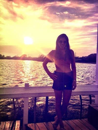 A girl poses in front of the sunset on the water in the Hamptons. 