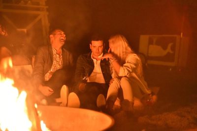 Friends laugh by the beach bonfire on a summer night in the Hamptons. 