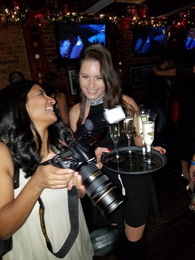 A waitress carrying a try of champagne laughing with a guest at a new year's eve party in NYC.