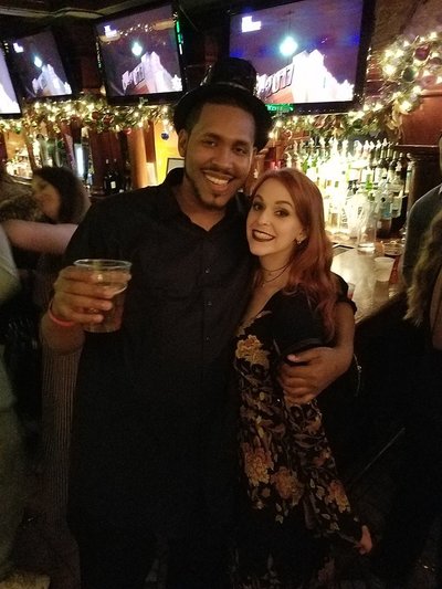 Two NYC professionals pose in front of the bar at a party in NYC. 