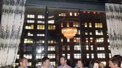 A group of friends sit in front of a window with a view of manhattan at a trendy party.