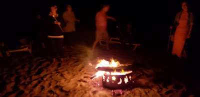 A group of young professionals from nyc ending their night out in the hamptons around a bonfire at private hotel beach