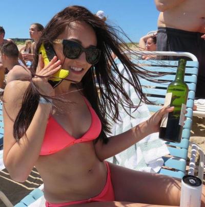 A woman on vacation  relaxes on a Hamptons beach with a bottle of wine. 