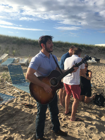 rabbi playing his guitar on a hamptons beach