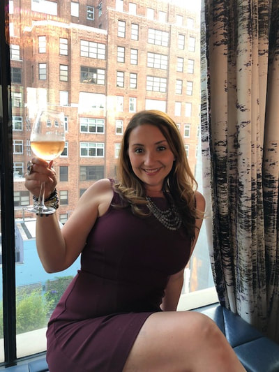Woman holding a glass of wine at a rooftop party for NYC singles. 